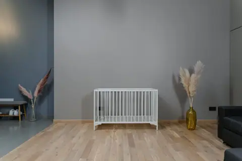 A modern minimalist nursery with a white crib and decor in earthy tones.